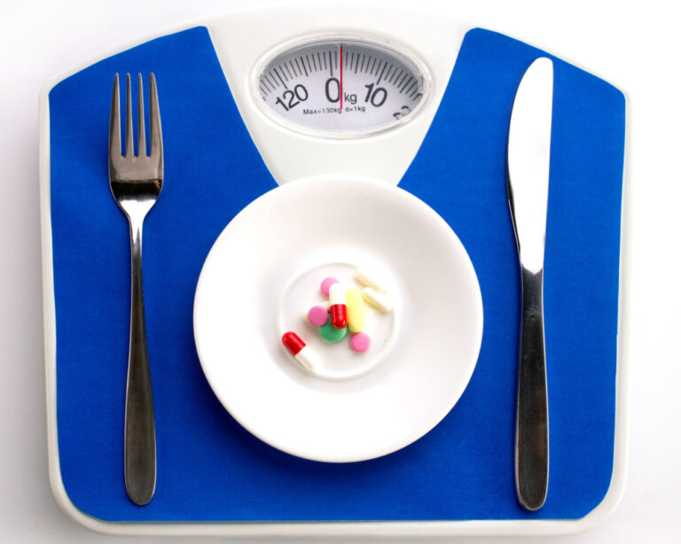 Blue scale with small plate with pills on it and knife and fork to the side to sympolize are weight loss pills safe