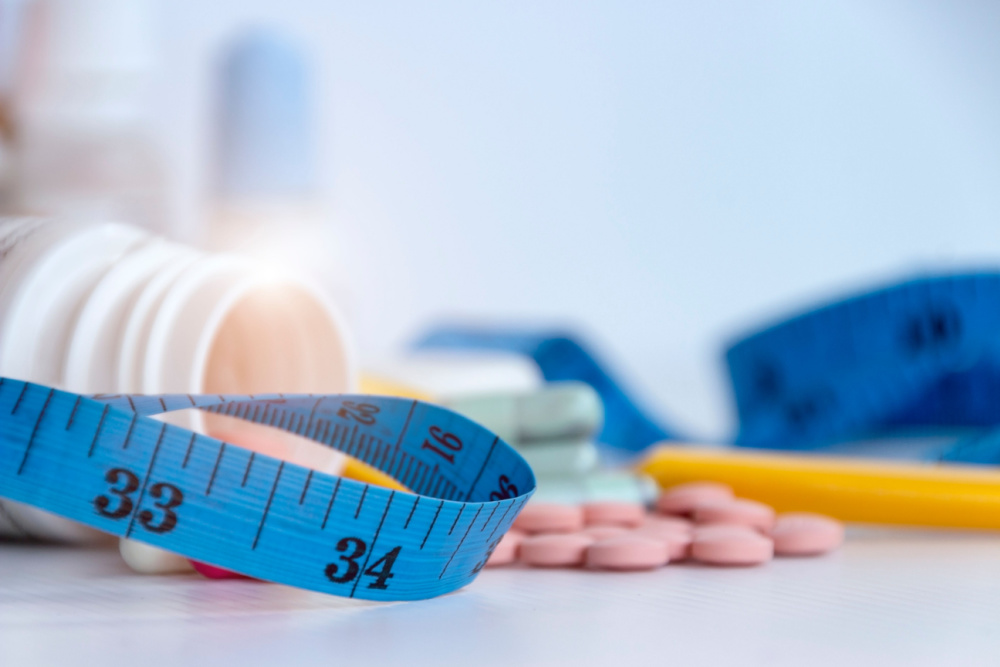 Image of blue cloth tape measure and keto weight loss pills.