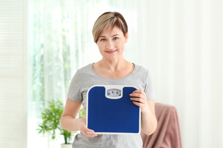 Woman holding scales in front of her to signify her success with medically supervised weight loss