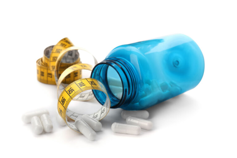 Blue bottle on its side with pills spilling out and a cloth tape measure to represent best prescription weight loss pillseight loss pills